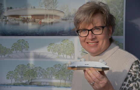Festspiele-Mitarbeiterin Kerstin Gradert hält das Modell in Händen, das Vorbild sein soll für den Neubau der Tribüne am Großen Eutiner See. Die Pläne sind jetzt im Gastro-Pavillon der Festspiele ausgestellt. Foto: EFS